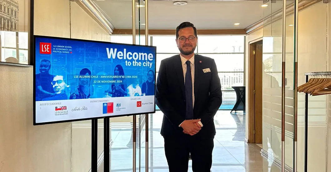 Felipe Tabilo stands beside a sign advertising the Welcome to the City event the Chilean Alumni Association hosted