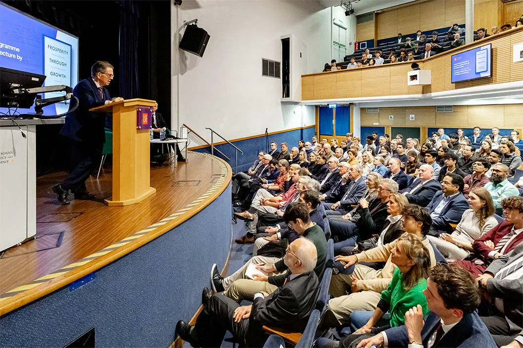 Guests sitting in rows listening the speaker on stage.