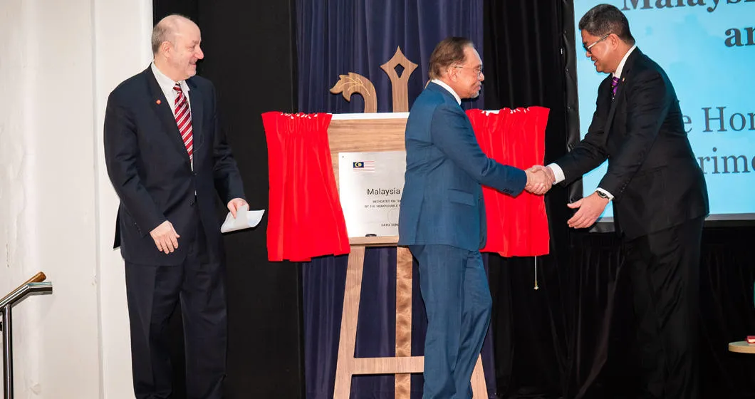 Anwar Ibrahim shakes Dato’ Azman Shah's hand after signing the plaque for the Malaysia Auditorium